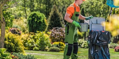 Professional gardener maintaining healthy garden beds with pruning tools in an Australian backyard